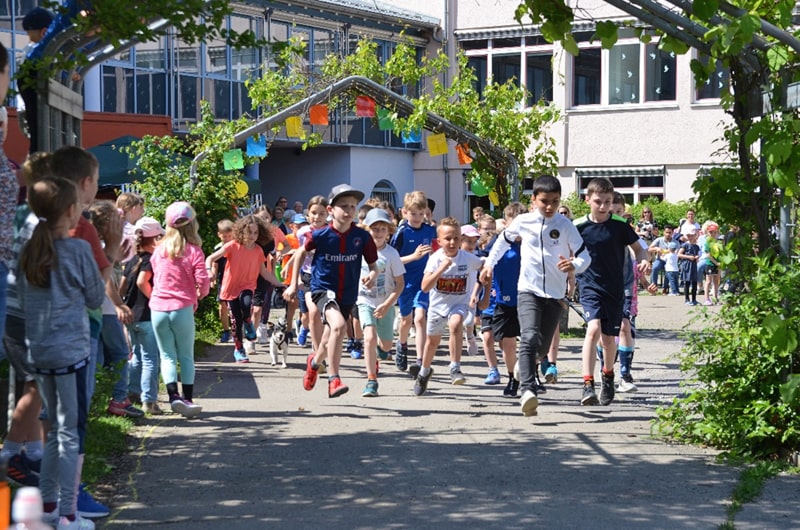 Start eines Wettlaufes vor der Schule, Kinder rennen los.